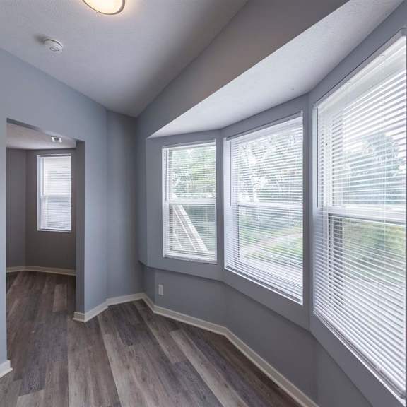 a room with grey walls and wooden flooring with a doorway leading to another room.