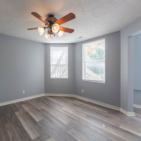 a room with a ceiling fan and wooden flooring.