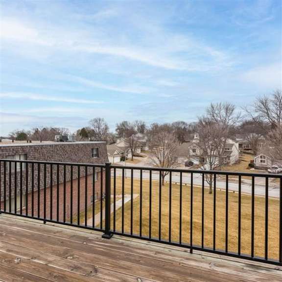 a balcony with a black railing overlooks a residential area.