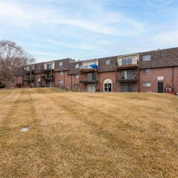 a grassy field in front of apartment buildings.
