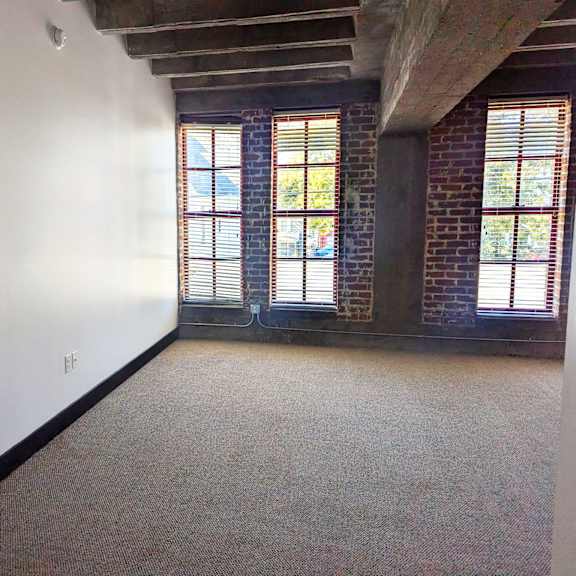 a room with a carpeted floor and a brick wall.