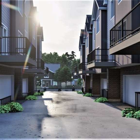 a sunny day in a residential area with apartment buildings on both sides of a paved road.