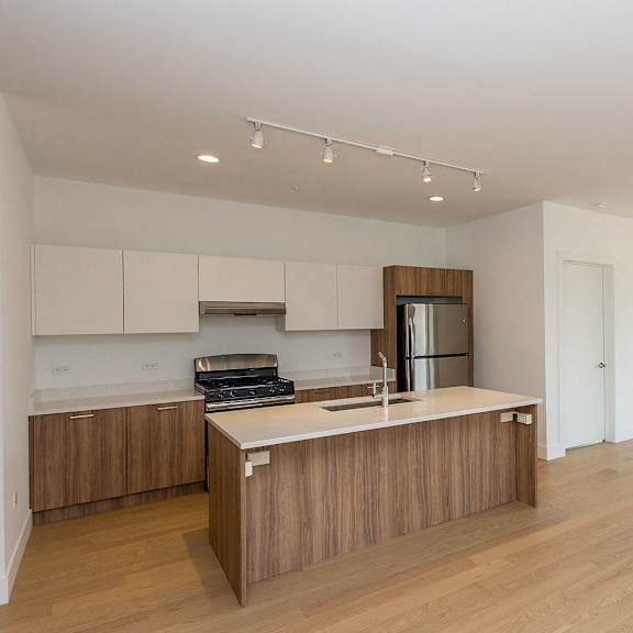 a kitchen with wooden cabinets and a counter top in an empty living room