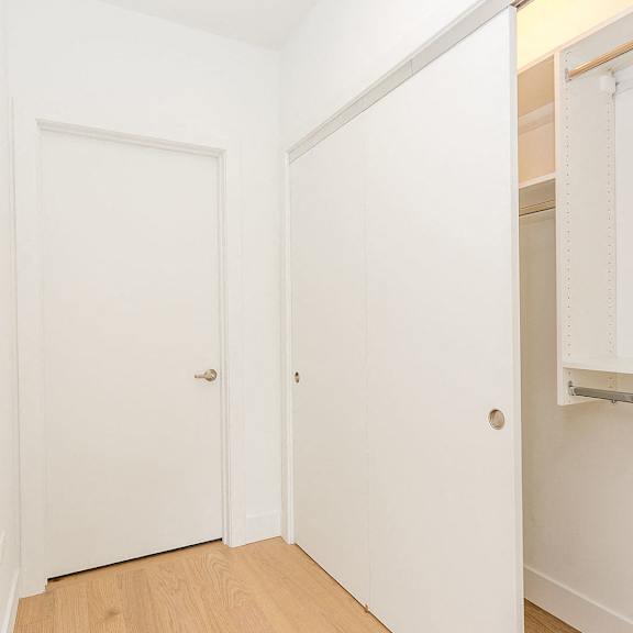 a bedroom with white walls and a closet and a door