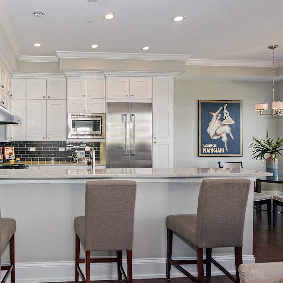 a kitchen with white cabinets and a bar with chairs