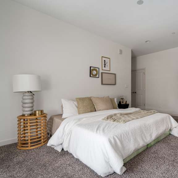 a bedroom with a white bed and a grey carpet.