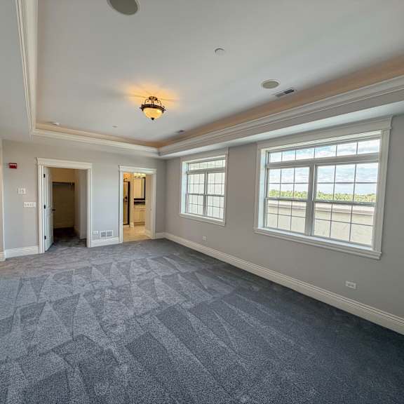 a large empty room with a patterned carpet and a window overlooking the sea.