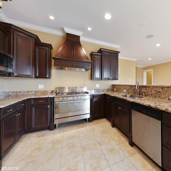 a large kitchen with granite counter tops and dark cabinets