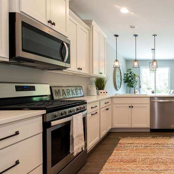 a kitchen with stainless steel appliances and white cabinets at countryside townhomes, illinois
