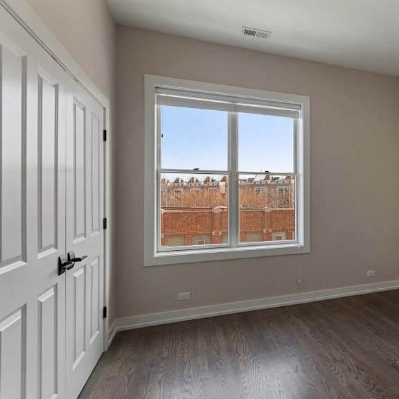 an empty living room with a window and wooden floors