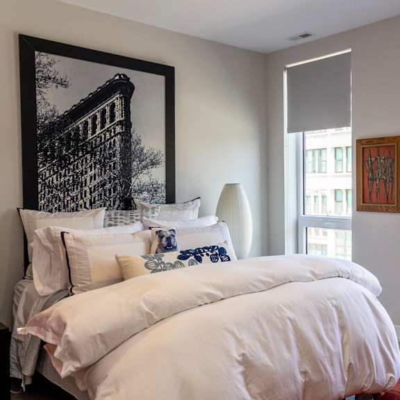 a bedroom with a bed and two windows and a painting on the wall