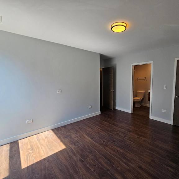 a living room with wood floors and a door to a bathroom