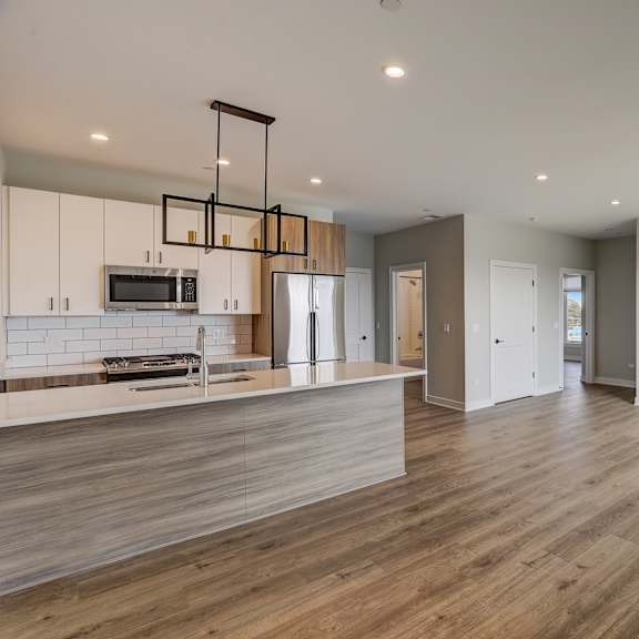 an open kitchen and living room with white cabinets and wood floors