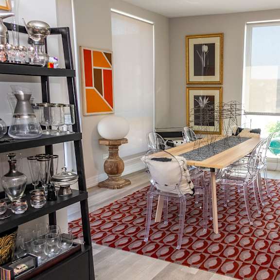 a dining room with a wooden table and chairs and a red rug