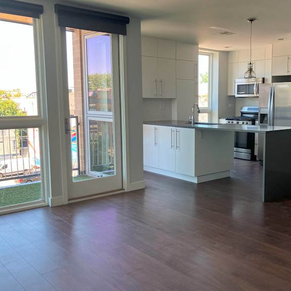 an open kitchen and living room with a wooden floor