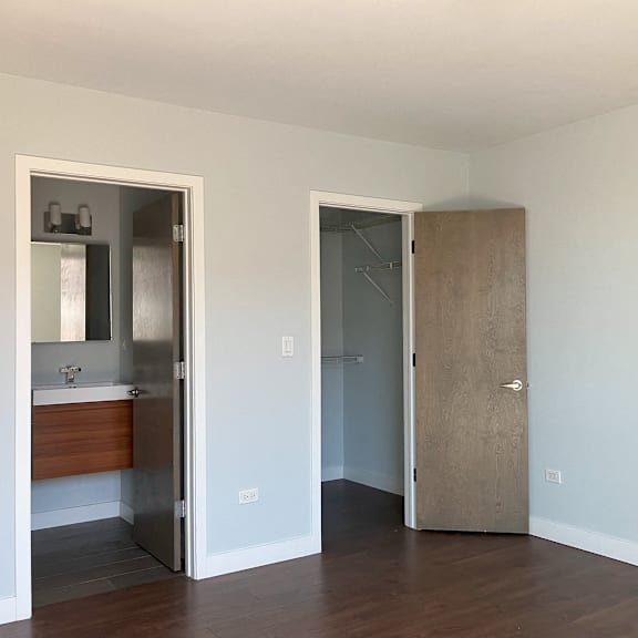 an empty room with a door to a bathroom and a mirror
