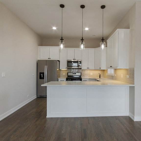a kitchen with white cabinets and a counter top and a refrigerator