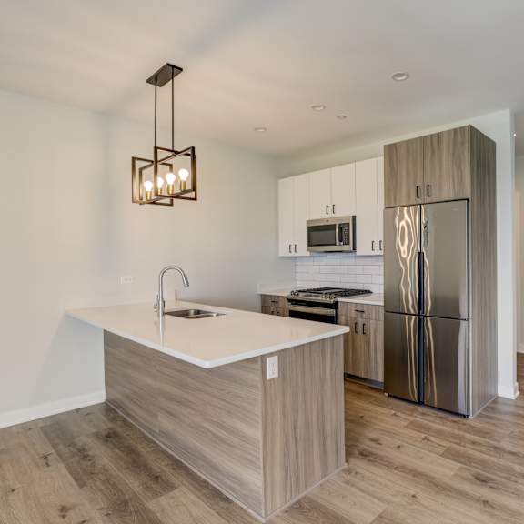 a kitchen with a large island and stainless steel refrigerator