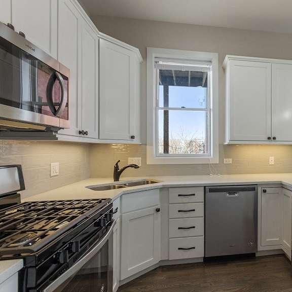 a kitchen with white cabinets and a stove and a window