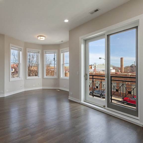 an empty living room with large windows and a wood floor