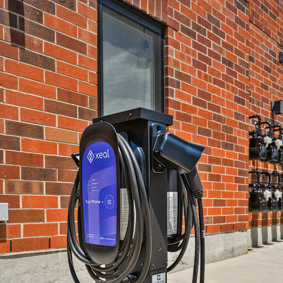 a black electric vehicle charging station with a blue screen and a long black cord.