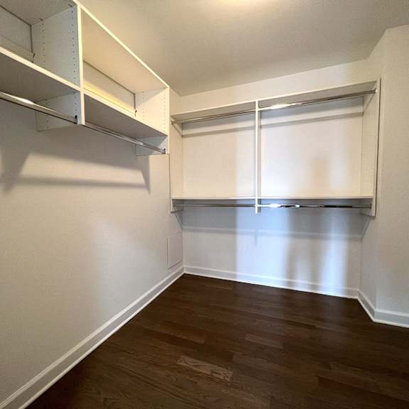 a living room with a wood floor and white walls and a closet with a window