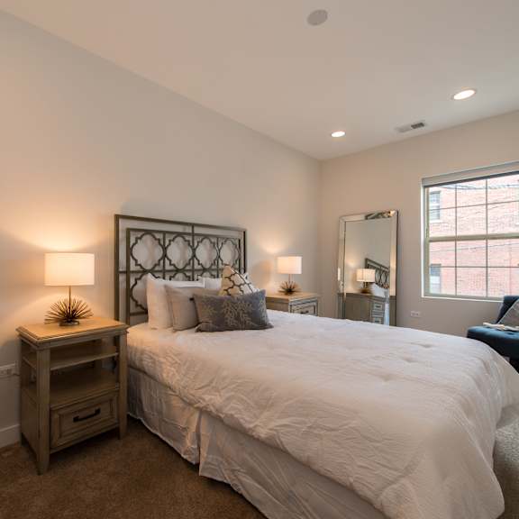 a bedroom with a bed and a chair and a window