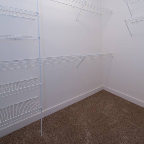 a walk in closet in a room with white walls and carpet