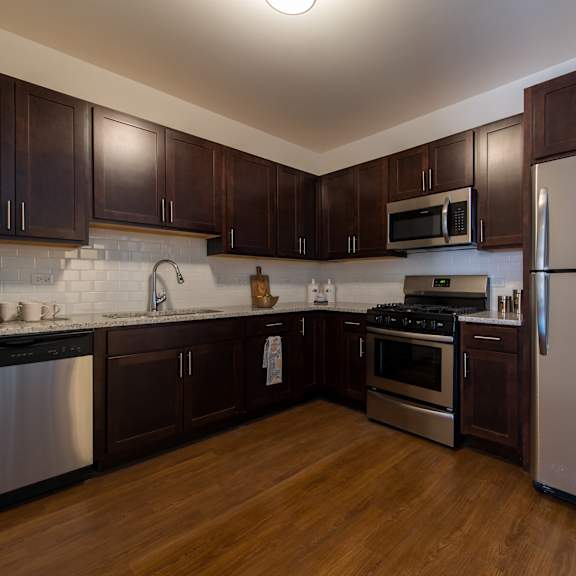 a kitchen with stainless steel appliances and dark wood cabinets