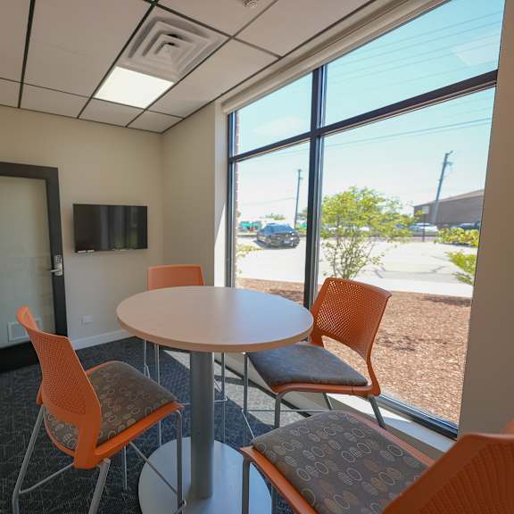 a room with a table and chairs in front of a window