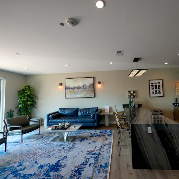 a living room with a kitchen and a blue rug