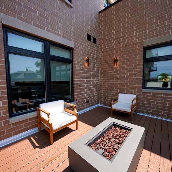 a covered patio with two chairs and a fire pit