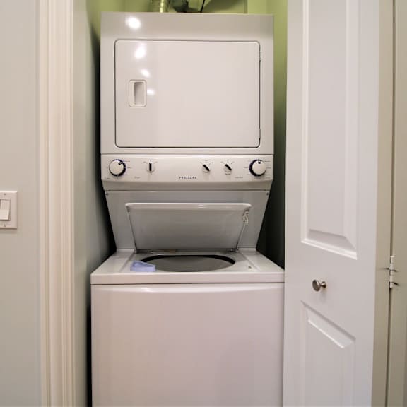 a white washing machine is in a small laundry room.