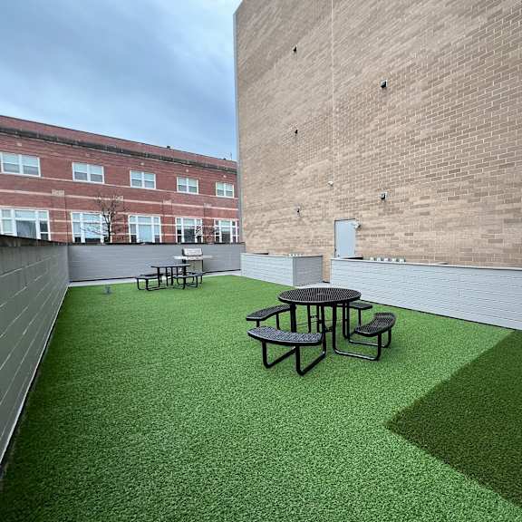 a roof deck with a table and chairs on a green lawn