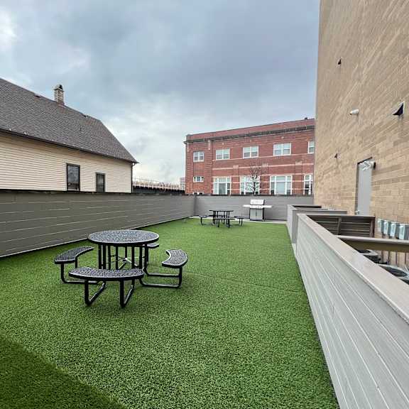 a rooftop patio with a green lawn and tables