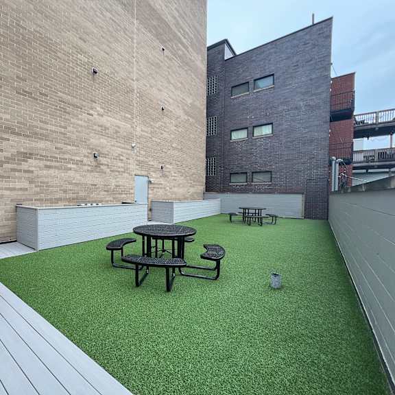a roof deck with a grill and a table and chairs on a green turf