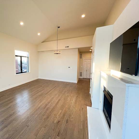 a spacious living room with wooden flooring and a fireplace.