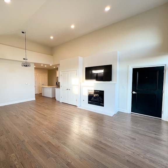 a spacious room with wooden flooring and a television mounted on the wall.
