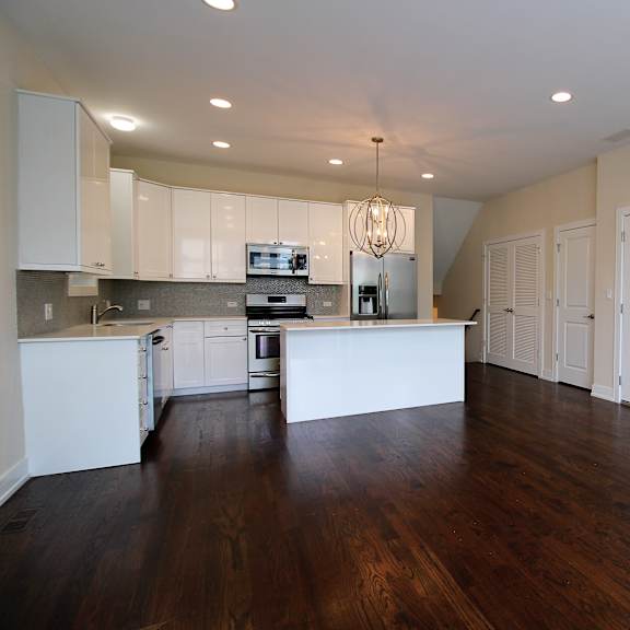 an empty kitchen with white cabinets and a counter top