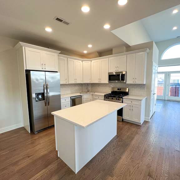 a kitchen with white cabinets and a white island.