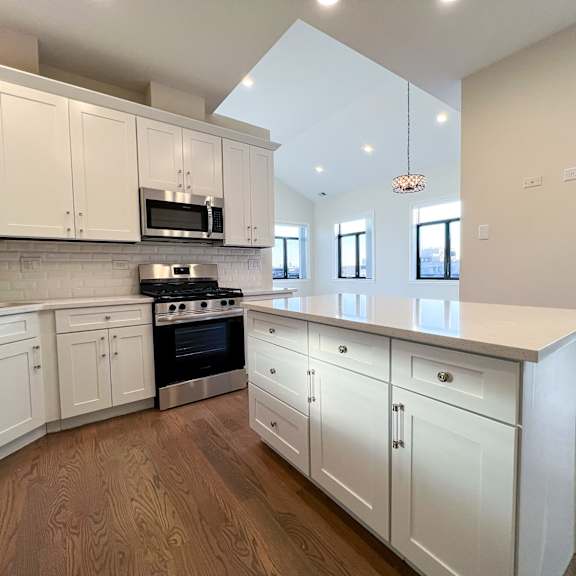 a kitchen with white cabinets and a wooden floor.
