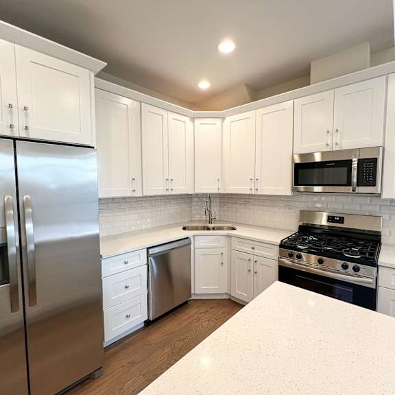 a kitchen with white cabinets and a stainless steel refrigerator.
