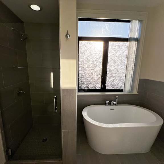 a white bathtub is in a bathroom with a glass shower door.