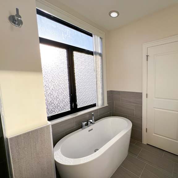 a white bathroom with a tub, sink, and window.