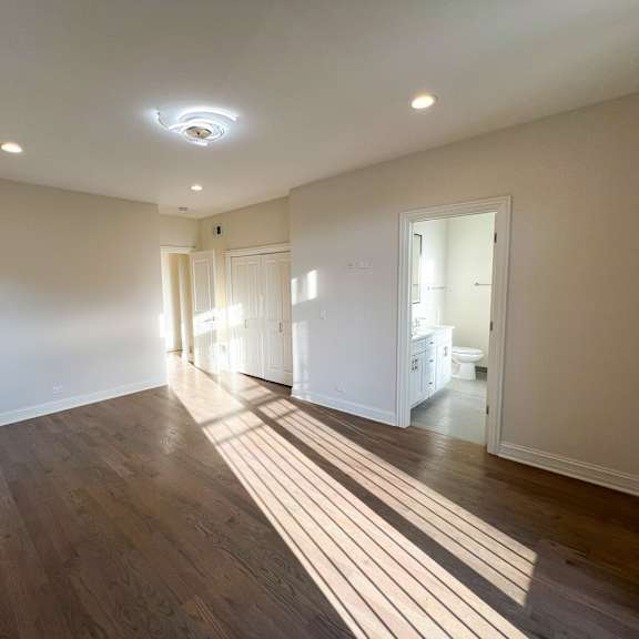a spacious room with wooden floors and white walls.