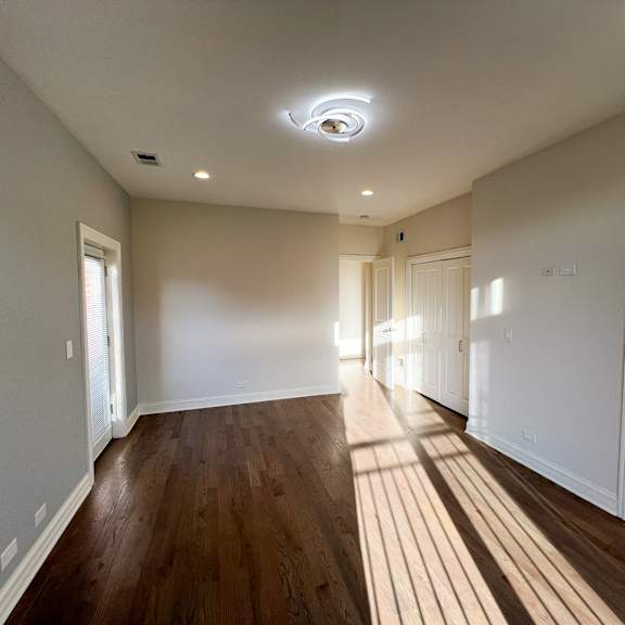 a spacious room with wooden floors and white walls.