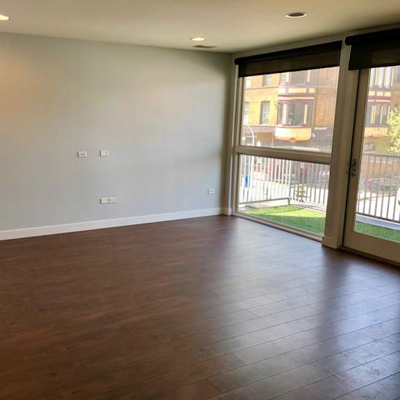 an empty living room with wood floors and a sliding glass door