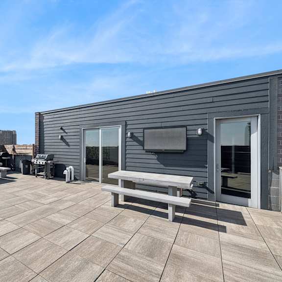 a rooftop patio with a table and chairs and a television.