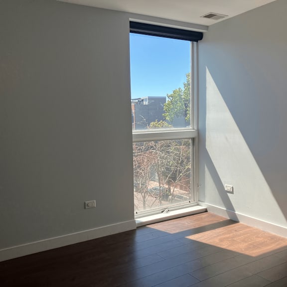 an empty living room with a large window and wooden floors