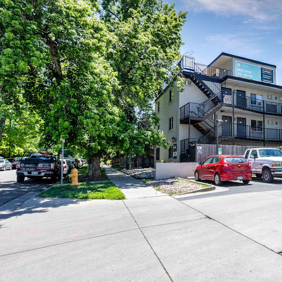 full view of modern apartment complex with tree-lined street, parking area, and updated exterior design at 1443 elizabeth in denver, co